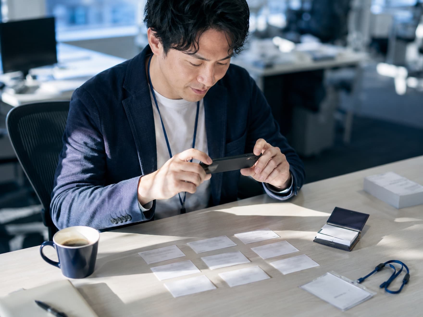 交流会の翌朝、机に並べた名刺をまとめてスマホで撮影している様子